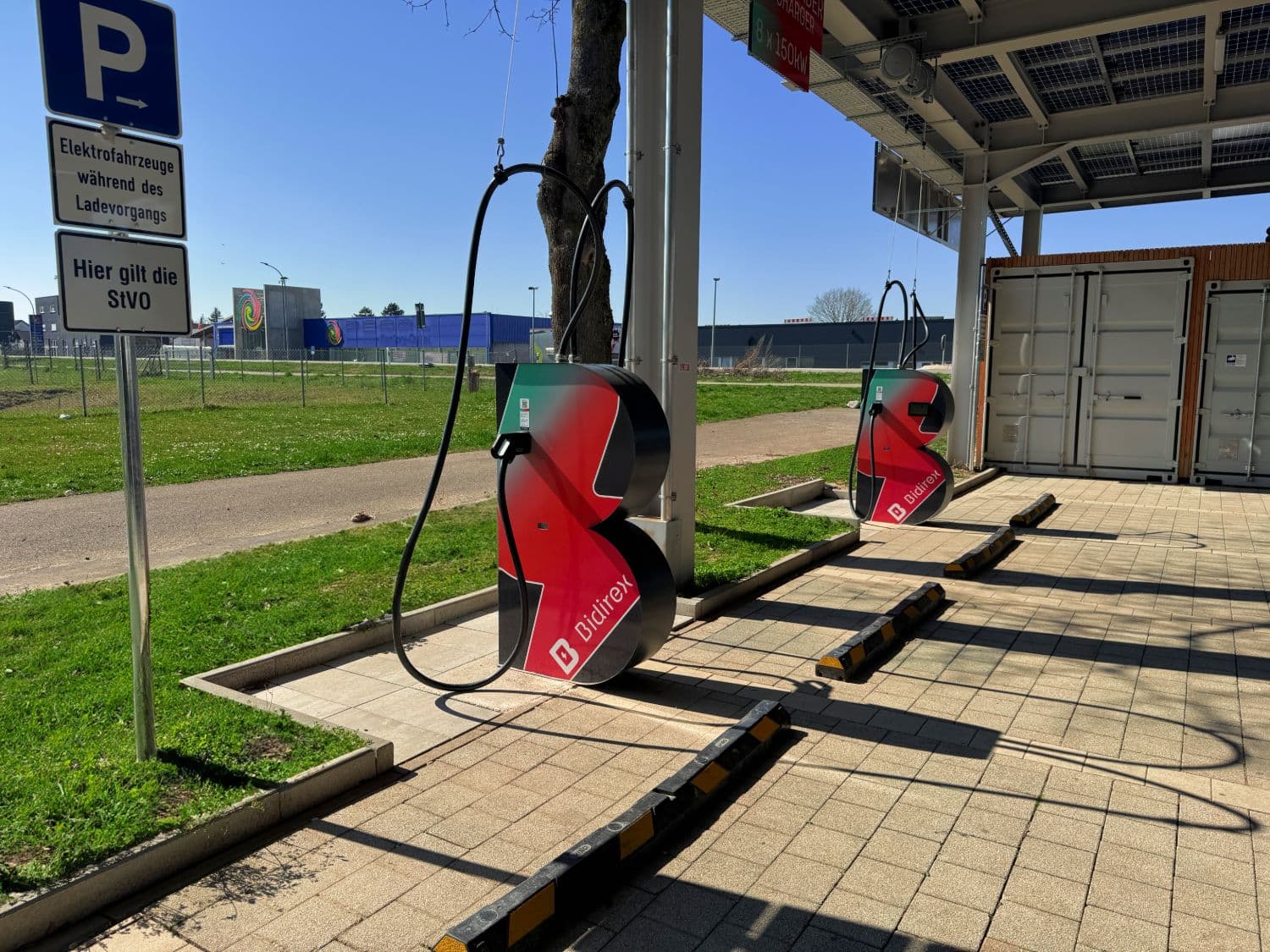 Reale Bidirex-Ladesäulen am Ladepark Auggen mit Technikcontainer im Hintergrund.